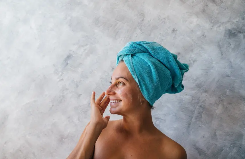 Beautiful young woman having facial mask with towel